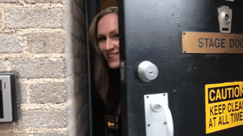 A GIF of Sara Bareilles opening a door and sticking her head out.
